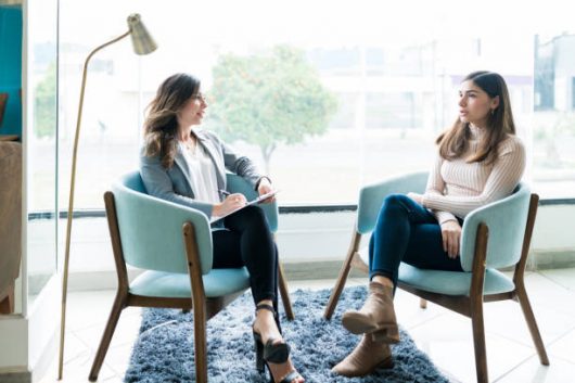 Young woman sharing her problems with female therapist during psychotherapy session in office